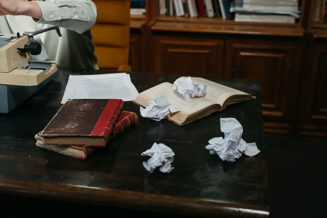 A cozy workspace with typewriter, open books, and crumpled papers on a wooden desk, perfect for creative inspiration. Argumentative essay guide: claims, reasons, warrants, and limits