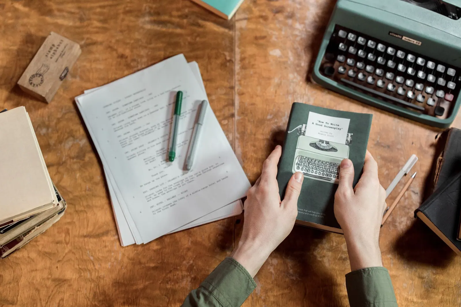 A vintage setup showcasing a typewriter, manuscripts, and hands holding a book on writing. Definition, process, causal, and systems explanations compared