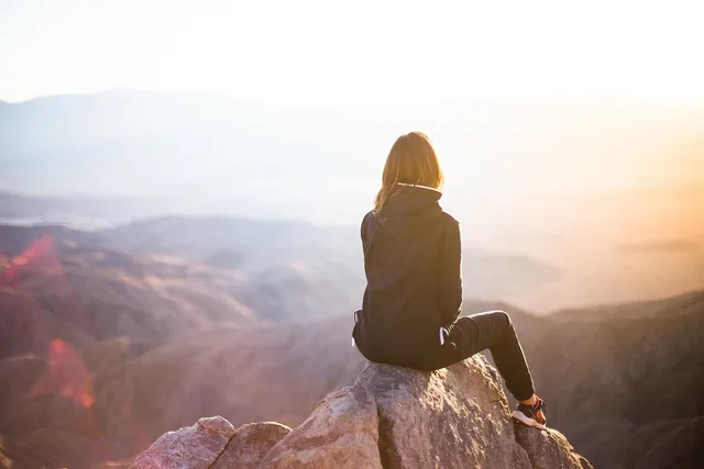 people, woman, travel, adventure, trek, mountain, rock, sunset, cliff, black, hoodie, jacket, alone, thinking, nature, freedom. Place writing problems: exoticism, scenery lists and false solitude