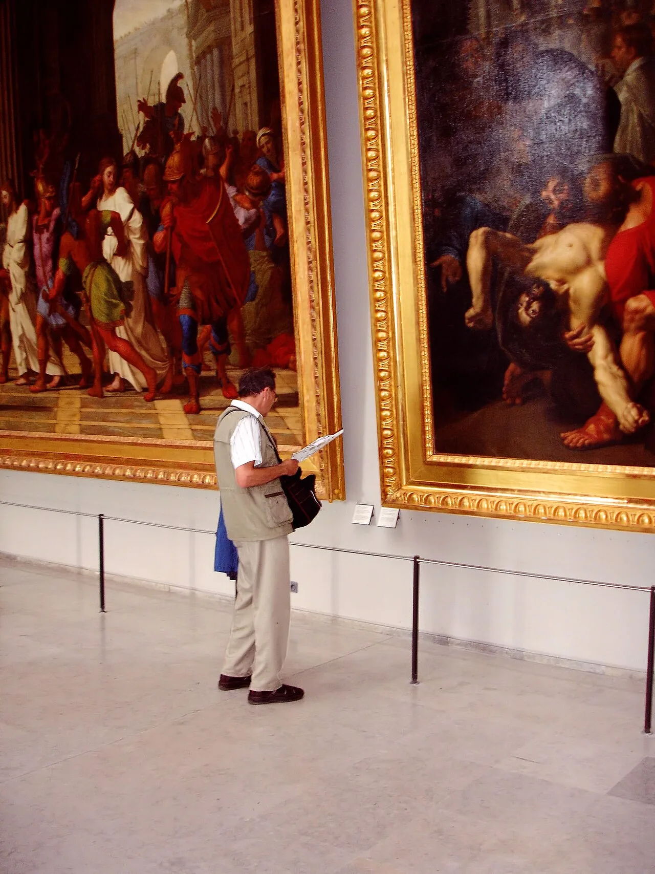 A museum visitor looking at paintings in the Louvre