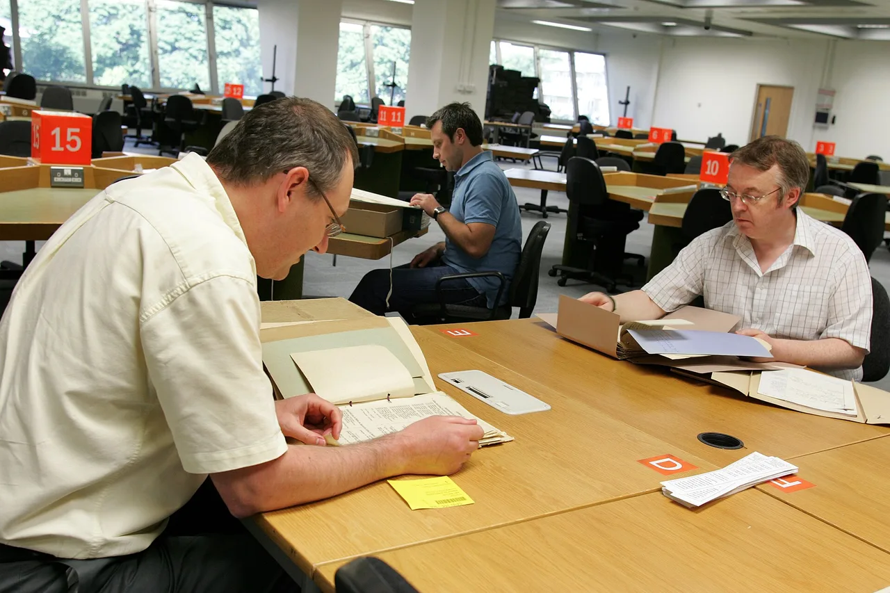 Researchers examining document folders in a reading room