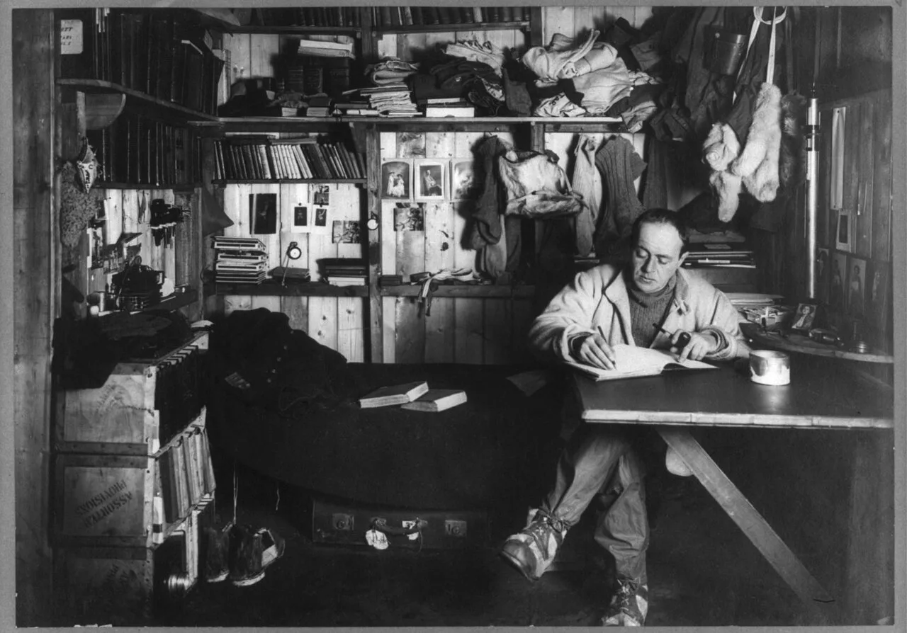 Robert Falcon Scott writing at a table during the Terra Nova expedition